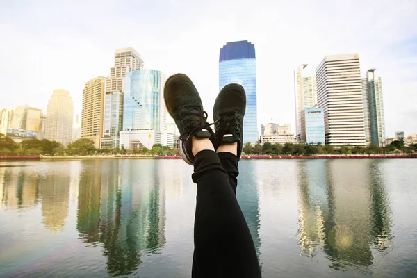 Feet point to the blue sky with modern city background.