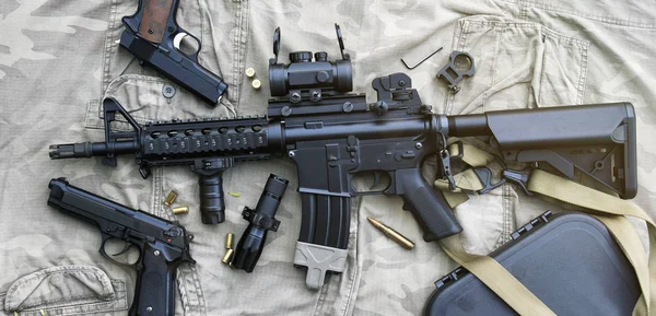 Armas y equipo militar para el ejército, rifle de asalto (M4A1) y pistola sobre fondo de camuflaje . — Foto de Stock