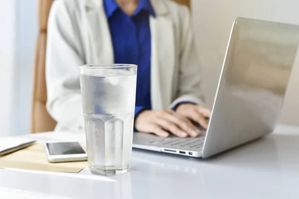 Ofiste bir bardak içme su ofis masasında çalışırken iş kadın içki taze iyi sağlık kavramı için içme suyu.