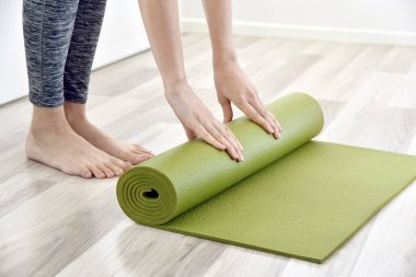 Kadın evde, ev egzersiz egzersiz çalışma dışarı sonra açık veya yoga mat katlama.