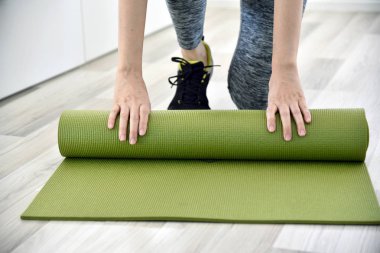 Kadın evde, ev egzersiz egzersiz çalışma dışarı sonra açık veya yoga mat katlama.