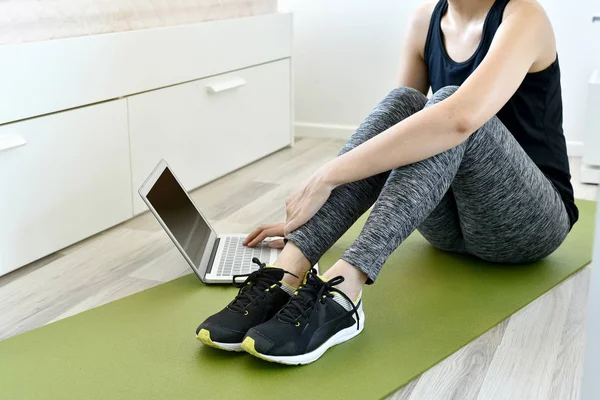 Young woman exercising at home doing yoga and looking at her tablet computer, Home exercise workout.