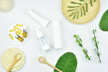 Kozmetik şişe kapları ile yeşil bitki yaprakları, mock-up marka için boş etiket paketi