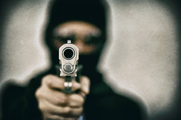Karnego bandyta z celem gun, zły facet w kapturze, trzymając pistolet pistolet. — Zdjęcie stockowe