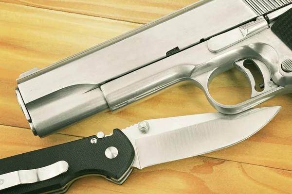 Pistola semiautomática y cuchillo táctico sobre fondo de madera . —  Fotos de Stock
