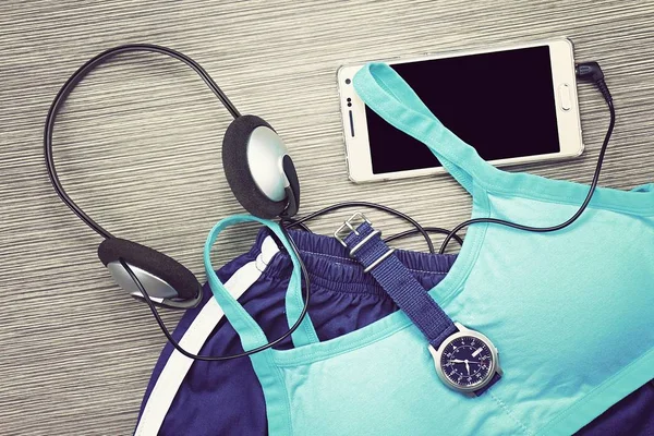 Roupa de ginástica - roupas de treino, tênis de corrida, fones de ouvido e smartphone para ouvir música enquanto faz exercício no centro de fitness — Fotografia de Stock