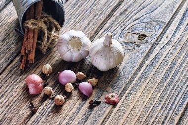 Çeşitli bitki ve baharat ahşap arka plan üzerinde. Soğancık, kakule, tarçın, taze sarımsak. Sağlıklı mutfak malzemeleri.