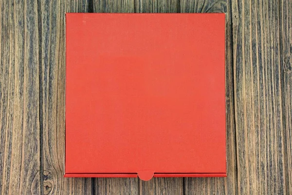 A red cardboard pizza box with copy space on wooden background. — Stock Photo, Image