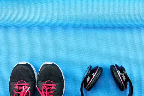 Fones de ouvido e sapatos esportivos no fundo tapete de ioga, Fitness e equipamentos de exercício, conceito de treino de entretenimento . — Fotografia de Stock