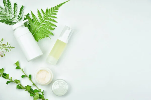 Kosmetické láhve kontejnery s zelených bylinek listy, prázdný popisek balíček pro branding maketa. — Stock fotografie