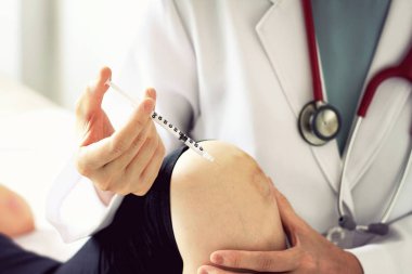 Doktor, iğne genç kadın hastaya veren inceleme diz ağrısı, spor, egzersiz yaralanma.