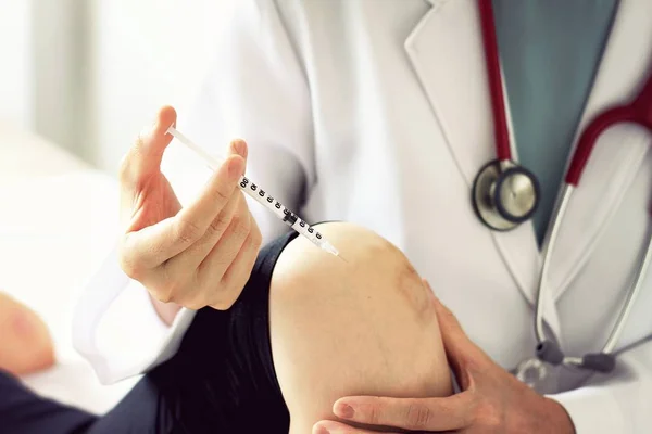 Médico administrando una inyección a una paciente joven, Examen del dolor de rodilla, Lesiones por ejercicio deportivo . — Foto de Stock