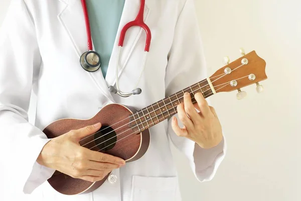 Ukulele, müzik terapi konsepti oynayan doktor. (Seçici odak)