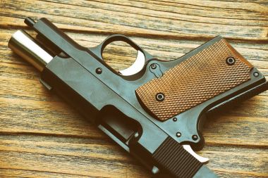 Küçük siyah silah (kompakt tabanca) yalan ahşap arka plan, 45'lik tabanca, kadın silah yakın çekim. (Renk işleme)