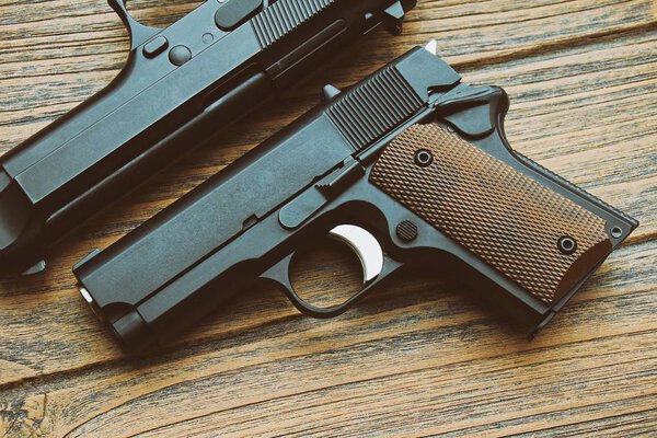 Close-up of small black gun (compact handgun) lying on wooden background, .45 pistol, Women gun.