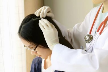 Kadın Doktor hastanın saç ve kafa derisi, dermatolog sınavına derisi bozukluğu bakarak.
