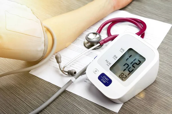 Dokter van meten van de bloeddruk van de patiënt, Digital Blood Pressure Monitor op hout achtergrond, medische behandeling van apparatuur. — Stockfoto