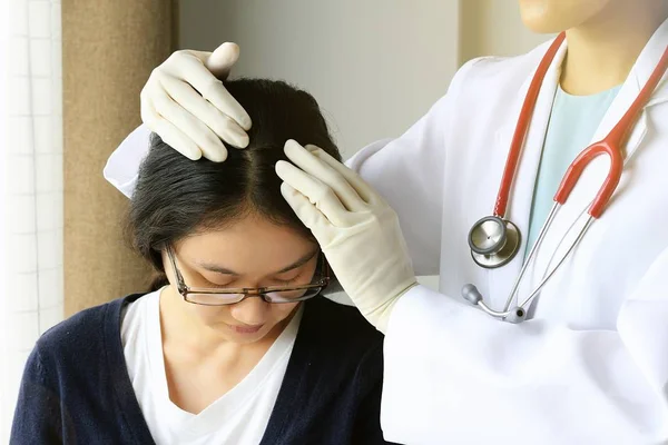 Kadın Doktor hastanın saç ve kafa derisi, dermatolog sınavına derisi bozukluğu bakarak.