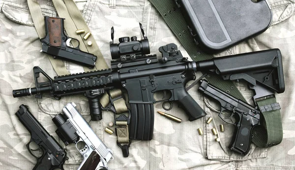 Armas y equipo militar para el ejército, rifle de asalto (M4A1) y pistola sobre fondo de camuflaje . — Foto de Stock