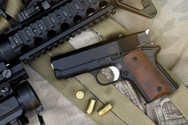 Close-up de armas e equipamentos militares para o exército, arma de rifle Assault e pequena pistola em fundo de camuflagem . — Fotografia de Stock