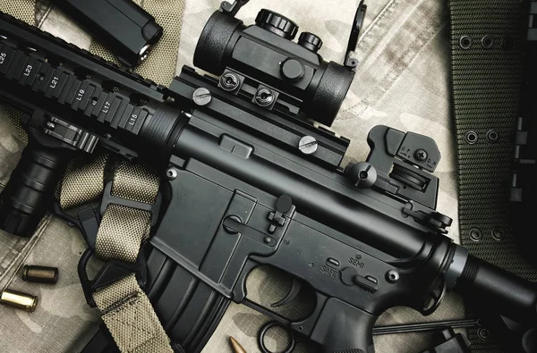 Close-up de um M4A1 armas e equipamentos militares para o exército, rifle Assault arma e pistola em fundo camuflagem . — Fotografia de Stock