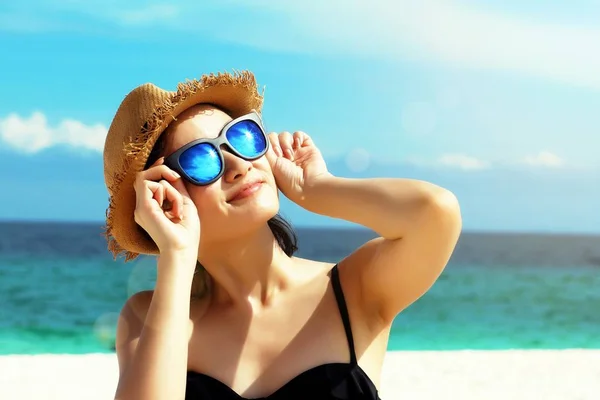 Unga kvinnliga mode modell leende och bär stora solglasögon på en strand, solskydd och hudvård koncept. — Stockfoto
