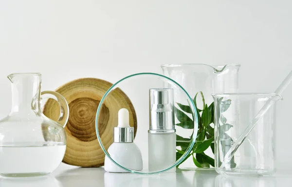 Kozmetikai üveg tartályok, zöld növényi levelek és tudományos üvegáruk, összpontosítani üres label csomag a modell — Stock Fotó