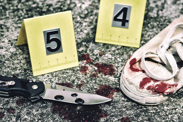 Investigaţia de la locul crimei, cuţitul sângeros şi pantofii victimei cu markeri criminali pe teren, dovezi de omucidere . — Fotografie, imagine de stoc