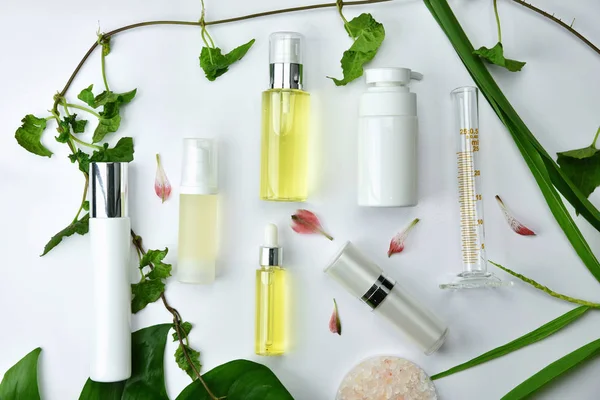 Contenitori per bottiglie cosmetiche con foglie di erbe verdi, confezione con etichetta bianca per il marchio mock-up, concetto di prodotto di bellezza biologico naturale . — Foto Stock