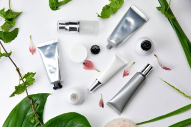 Kozmetik şişe kapları ile yeşil bitki yaprakları, marka mock-up, doğal organik güzellik ürün kavramı için boş etiket paketi.