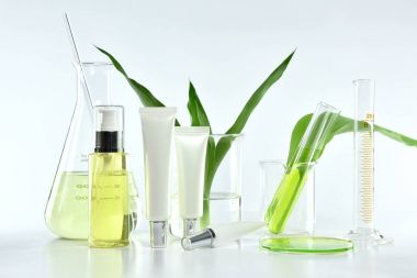 Yeşil bitkisel yapraklı kozmetik şişe kapları ve bilimsel cam eşyalar, markalaştırma, araştırma ve doğal organik güzellik ürünleri konseptini geliştirmek için boş etiket paketi..