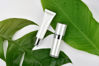 Yeşil bitkisel yapraklı kozmetik şişe kapları, markalaşma için boş etiket, doğal güzellik ürünü konsepti.