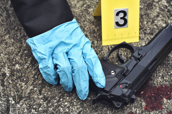 Расследование места преступления, пистолет с пятном крови на маркере преступления на земле
.