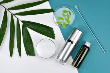 Kozmetik şişe kapları ile yeşil bitki yaprakları, boş etiket markalama mock-up, doğal güzellik ürün kavramı, için düz renk arka plan üzerinde yatıyordu..