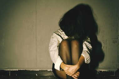Depresyonda ve hayal kırıklığına uğramış, karanlık odada oturan üzgün kadın.