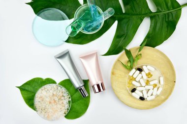 Kozmetik şişe kapları ile yeşil bitki yaprakları.