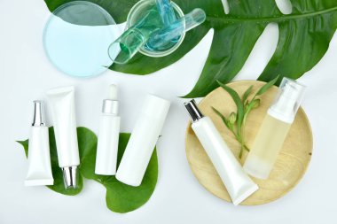 Yeşil bitkisel yapraklı kozmetik şişe kapları, markalaşma için boş etiket, doğal güzellik ürünü konsepti.