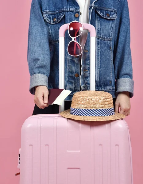 Junge Reisende mit rosa Koffer und Reisepass vor rosa Hintergrund, Reise- und Reisekonzept. — Stockfoto