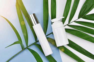 Kozmetik şişe kapları ile yeşil bitki yaprakları, boş etiket markalama mock-up, doğal güzellik ürün kavramı, için düz renk arka plan üzerinde yatıyordu..