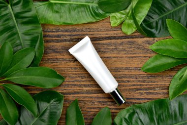 Kozmetik şişe kapları ile yeşil bitki yaprakları, marka mock-up, doğal organik güzellik ürün kavramı için boş etiket paketi.