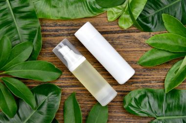 Kozmetik şişe kapları ile yeşil bitki yaprakları, marka mock-up, doğal organik güzellik ürün kavramı için boş etiket paketi.