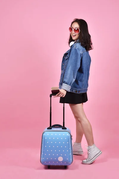 Koncepcja wakacje i podróże, podróżnik kobieta Smiling gospodarstwa walizkę i paszportu dokument na różowym tle. — Zdjęcie stockowe