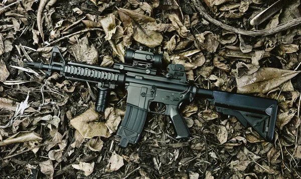 Armas e equipamentos militares para exército, arma de rifle de assalto (M4A1) e pistola em folhas secas fundo floresta . — Fotografia de Stock