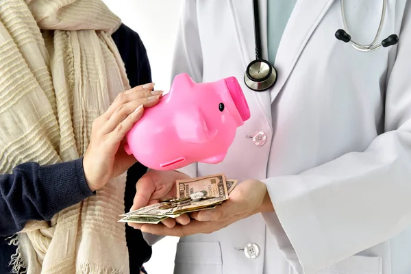 Health insurance concept, Patient paying doctor for medical service with money dollar banknote, Medical cost expense saving in piggy bank.