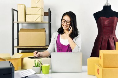 Online iş, e-iş ticaret, kontrol ve teslimat için online sipariş satış sırasında mevsimlik ambalaj küçük işletme sahibi için evde genç Asyalı kadın çalışma.