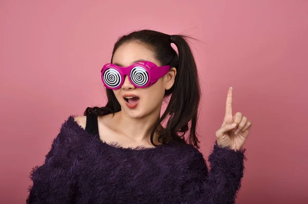 Asiatique femme main doigt point présentation produit pour la publicité, Bonheur fille portant des lunettes drôles avec plus excitant wow sentiment . — Photo