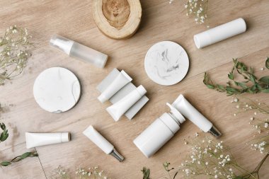 Yeşil bitkisel yapraklarla paketlenmiş kozmetik şişe kapları, organik markalaştırma için boş etiket, doğal cilt bakımı ürün konsepti.