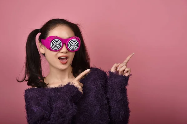 Asiatique femme main doigt point présentation produit pour la publicité, Bonheur fille portant des lunettes drôles avec plus excitant wow sentiment . — Photo