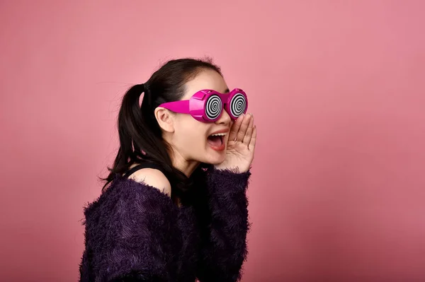 Surpris femme asiatique, crier fille portant des lunettes drôles sur fond rose isolé, Wow sentiments visage avec espace de copie pour la publicité . — Photo