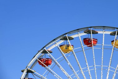 Dönme dolap, lunaparktaki berrak mavi gökyüzü arka planında ufukta gezinen renkli zevk tekerlekleri, çocukluk mutlu hatıralar ve eğlence zamanı, minimum stil..